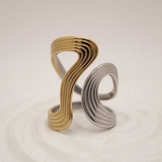 Gold and silver spiral ring on a beige background