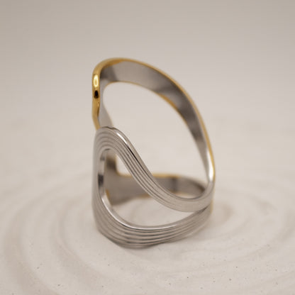 Silver ring with gold accent on a beige background