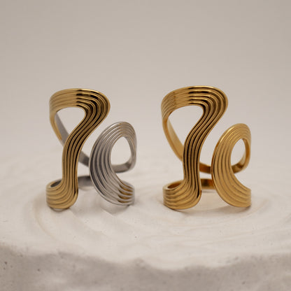 Two gold and silver rings with wavy designs on a beige background