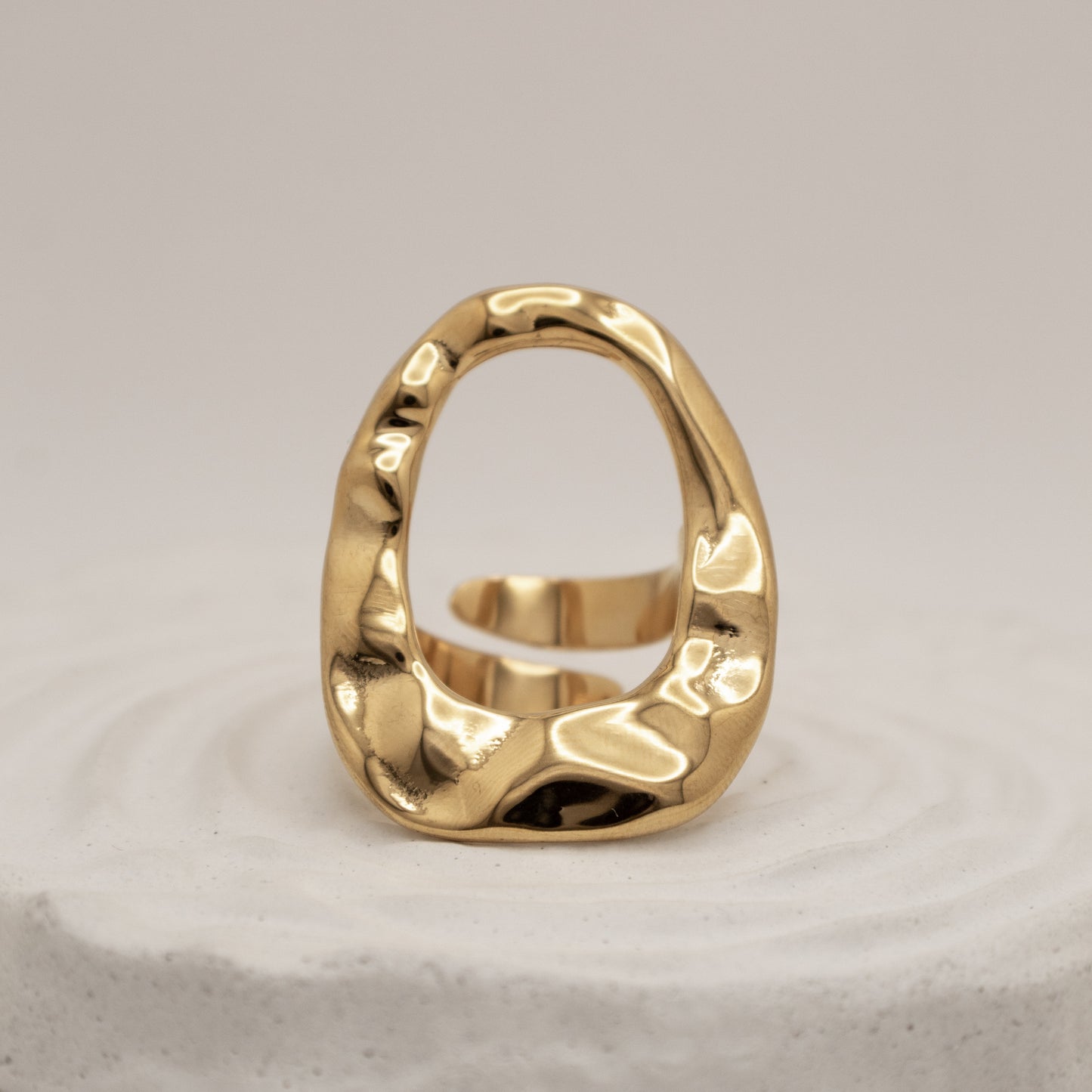 Gold ring with a textured design on a light gray background