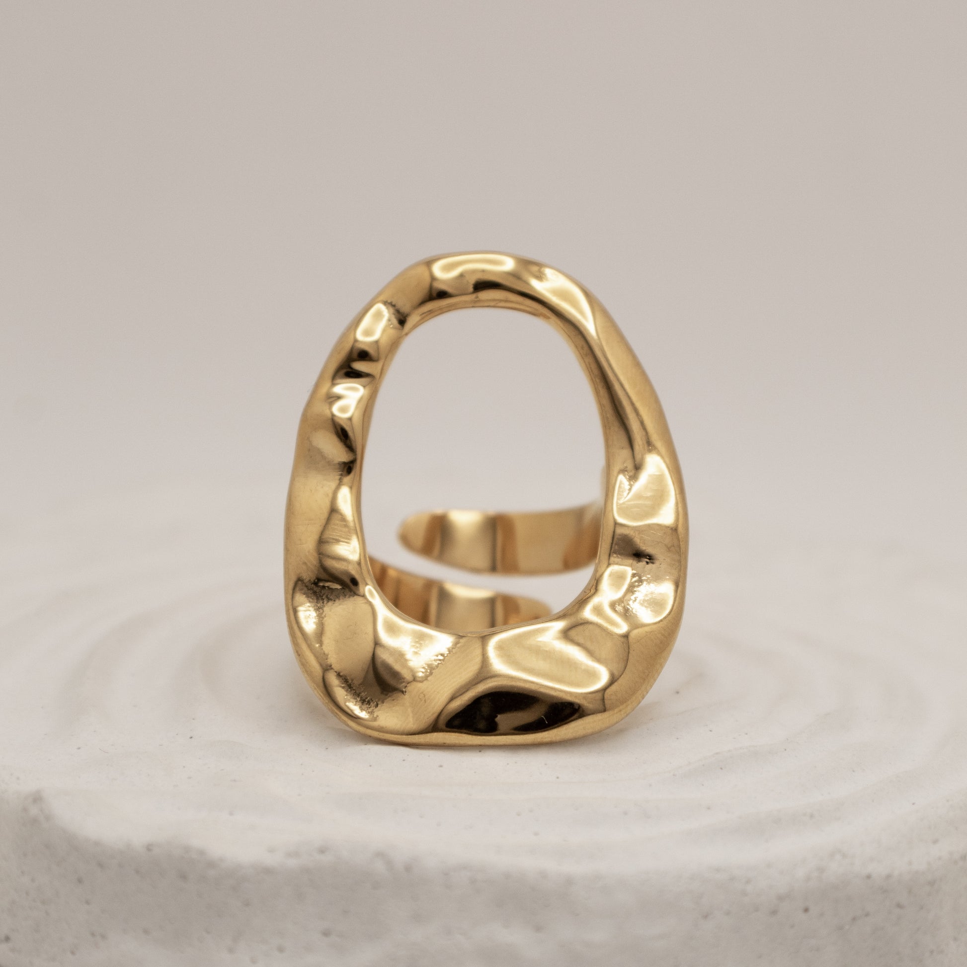Gold ring with a textured design on a light gray background