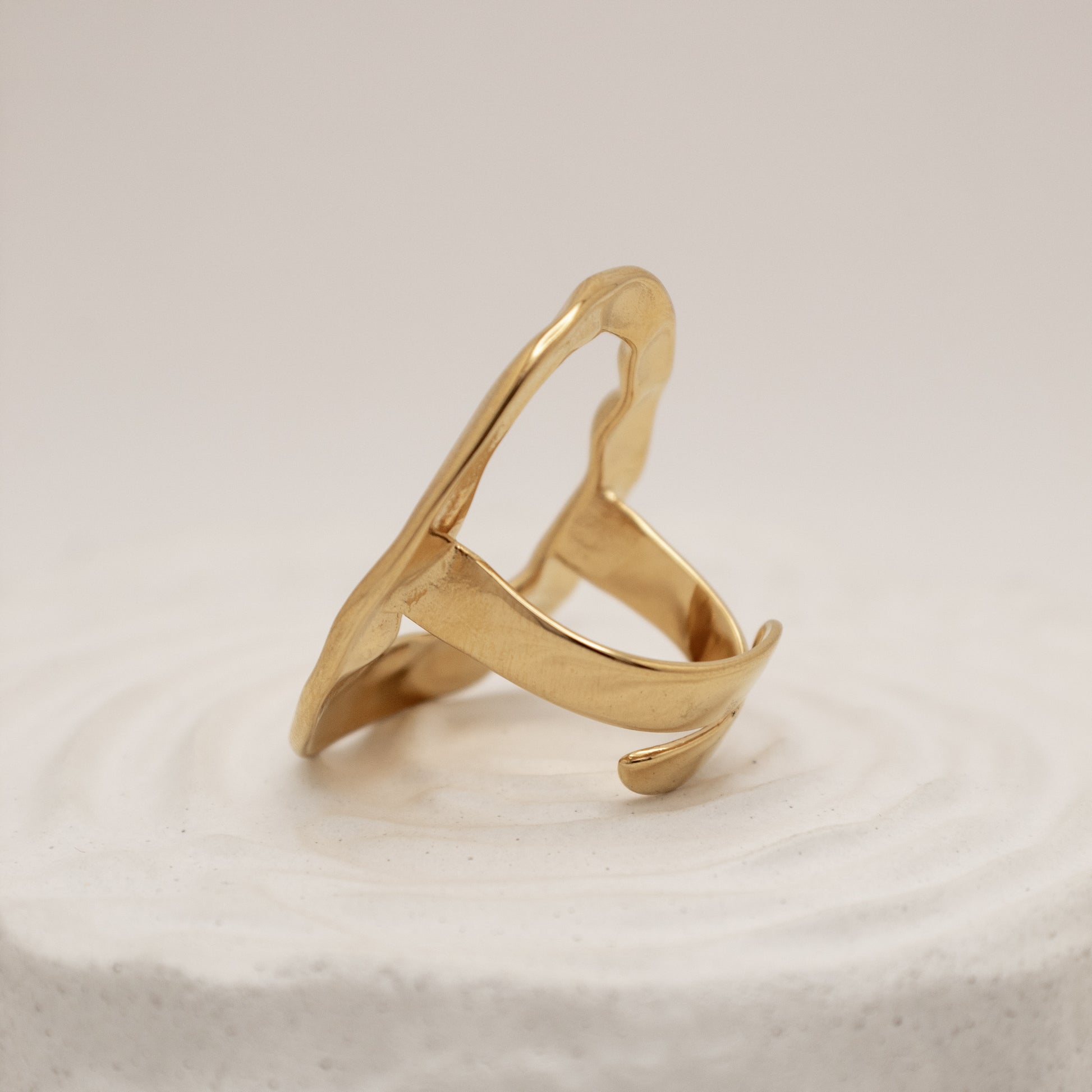Gold ring with a unique design on a light beige background