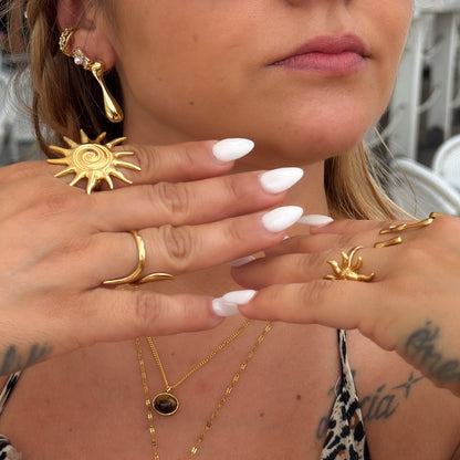 Close-up of a woman's hands wearing gold jewelry with sun designs.