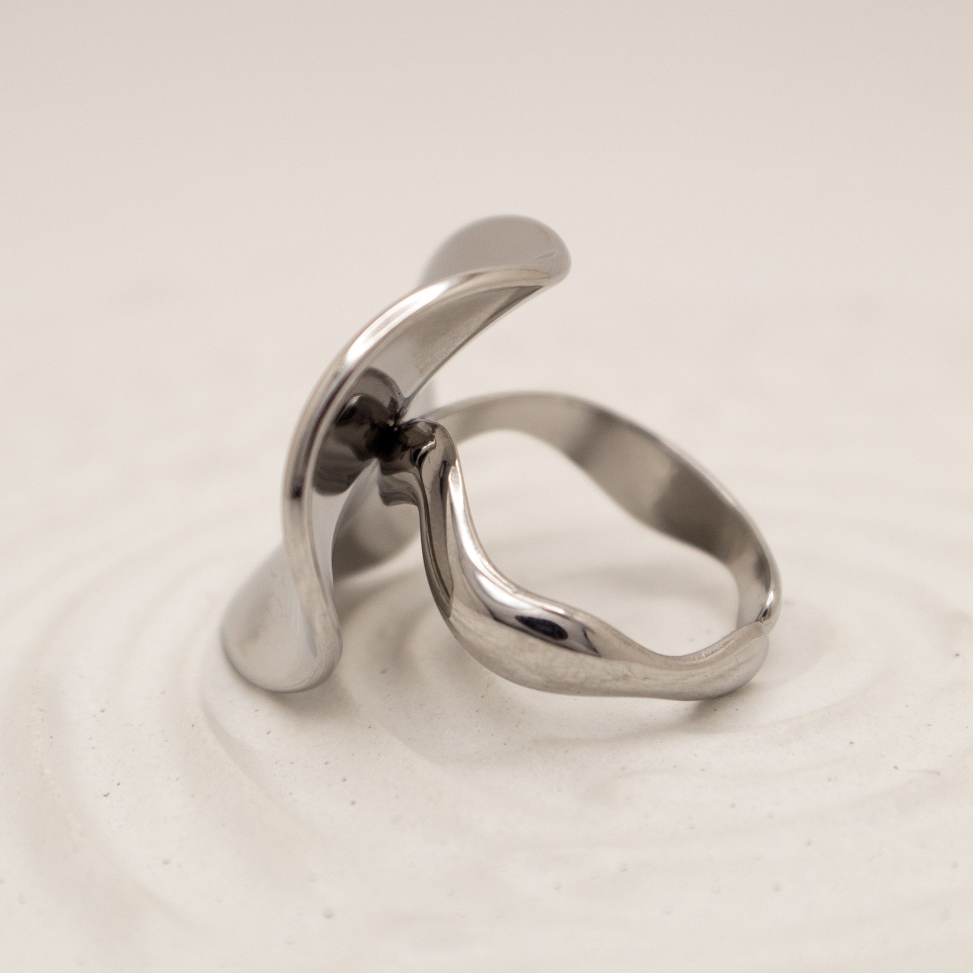 Silver ring with a modern design on a light beige background