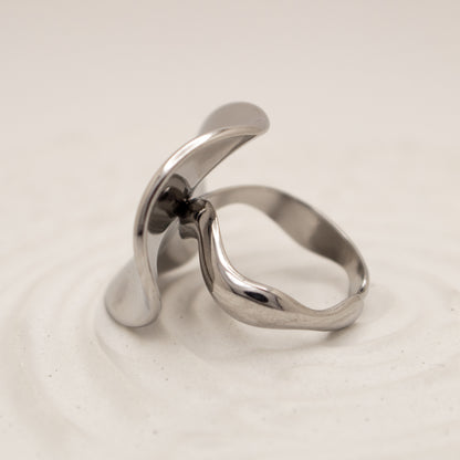 Silver ring with a modern design on a light beige background