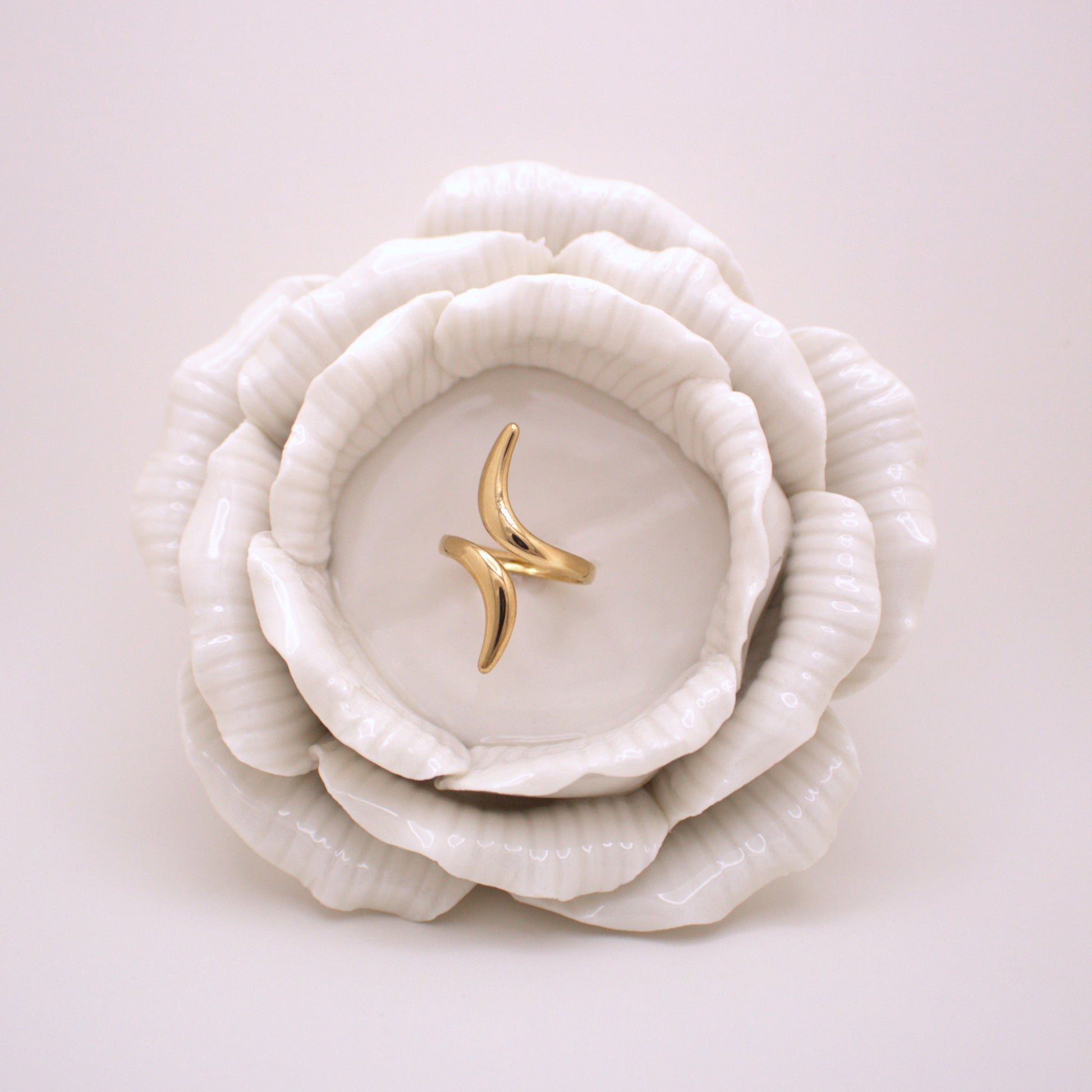 Gold ring on a white ceramic dish shaped like a flower