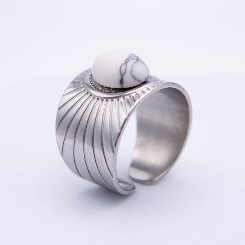 A silver-toned open band ring featuring a textured, ribbed exterior and a smooth white stone with gray veining set on top, photographed on a clean white background.