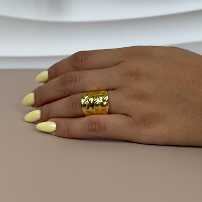 Hand wearing a gold ring with a neutral background