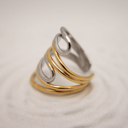Three metallic rings in gold, silver, and bronze on a light beige background