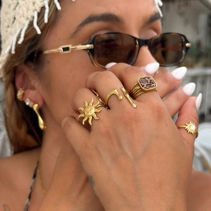 Close-up of a person wearing gold jewelry including rings and earrings.