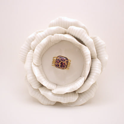 White ceramic flower with a leopard print hair clip inside on a white background