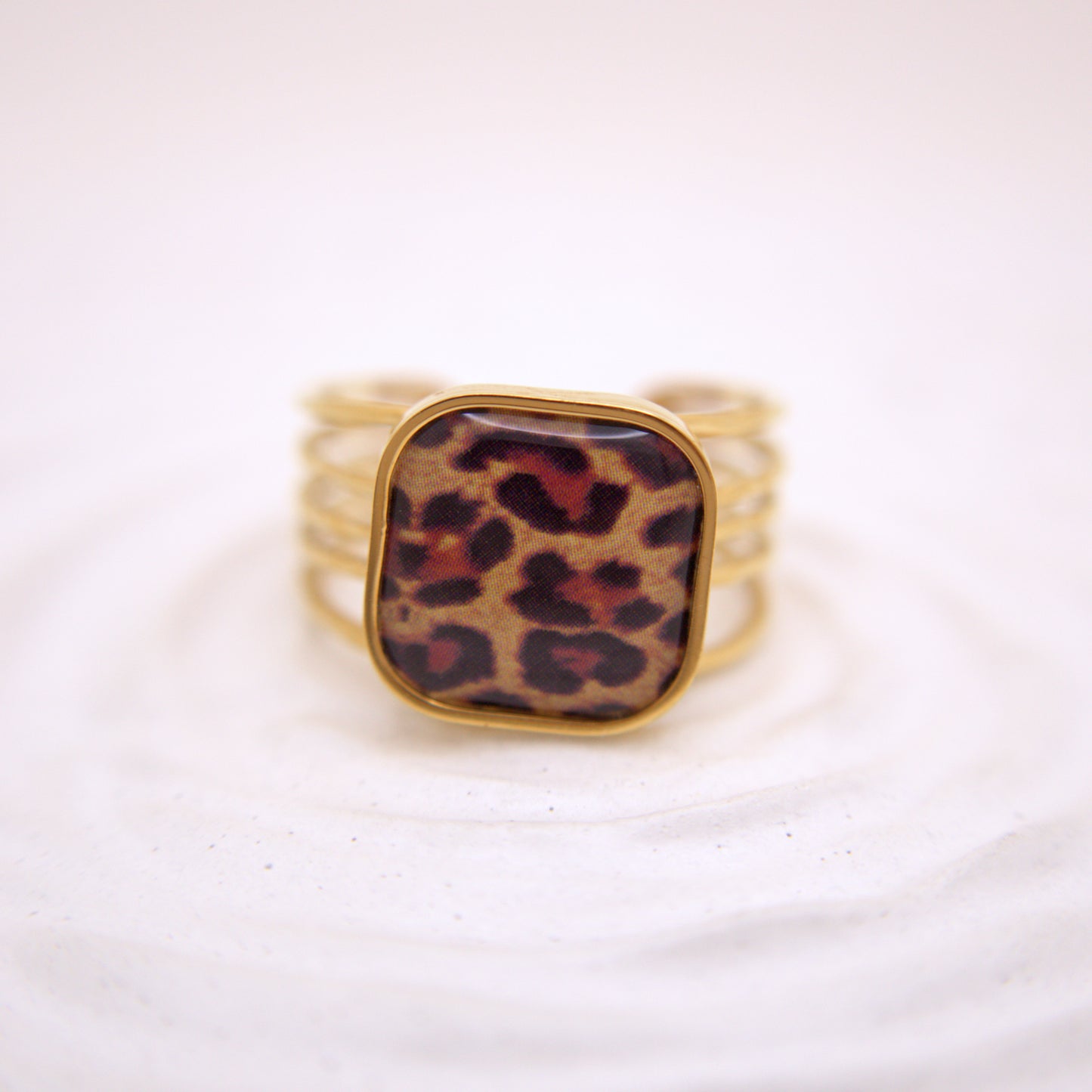 Gold ring with a leopard print stone on a white background