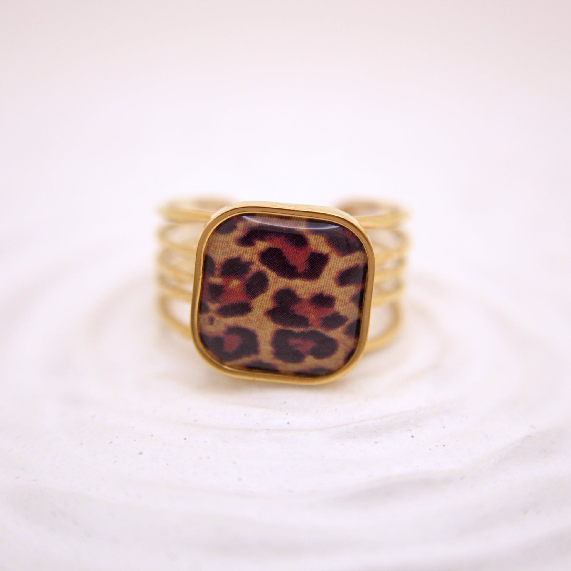 Gold ring with a leopard print stone on a white background