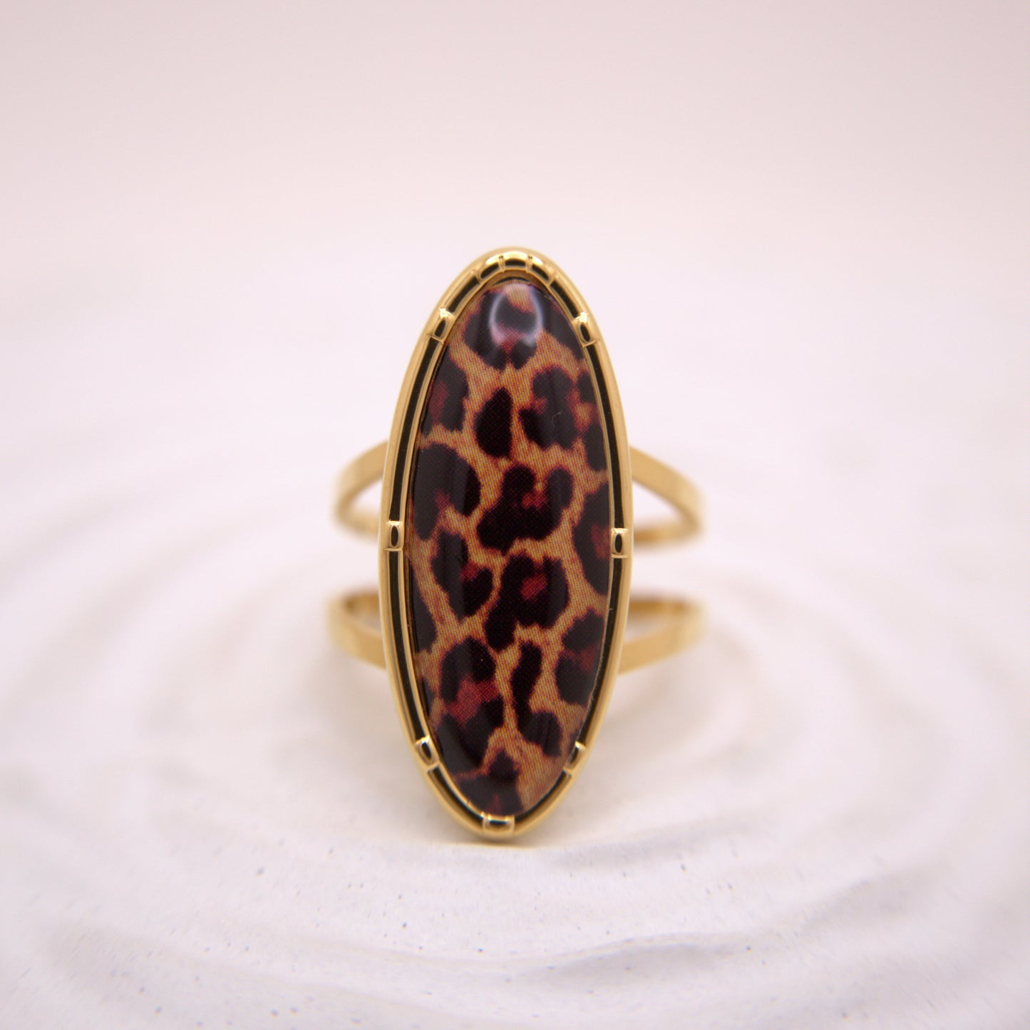 Gold ring with a leopard print stone on a white background