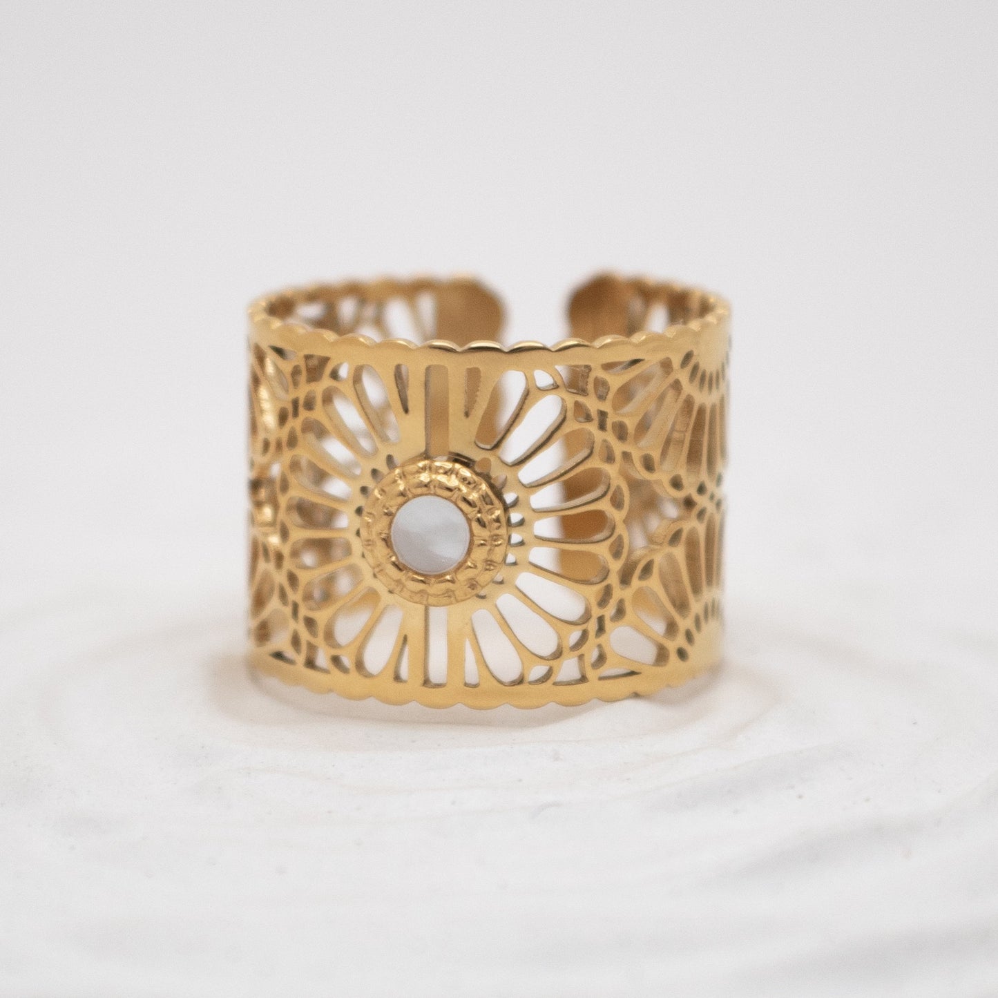Gold cuff bracelet with intricate design on a white background