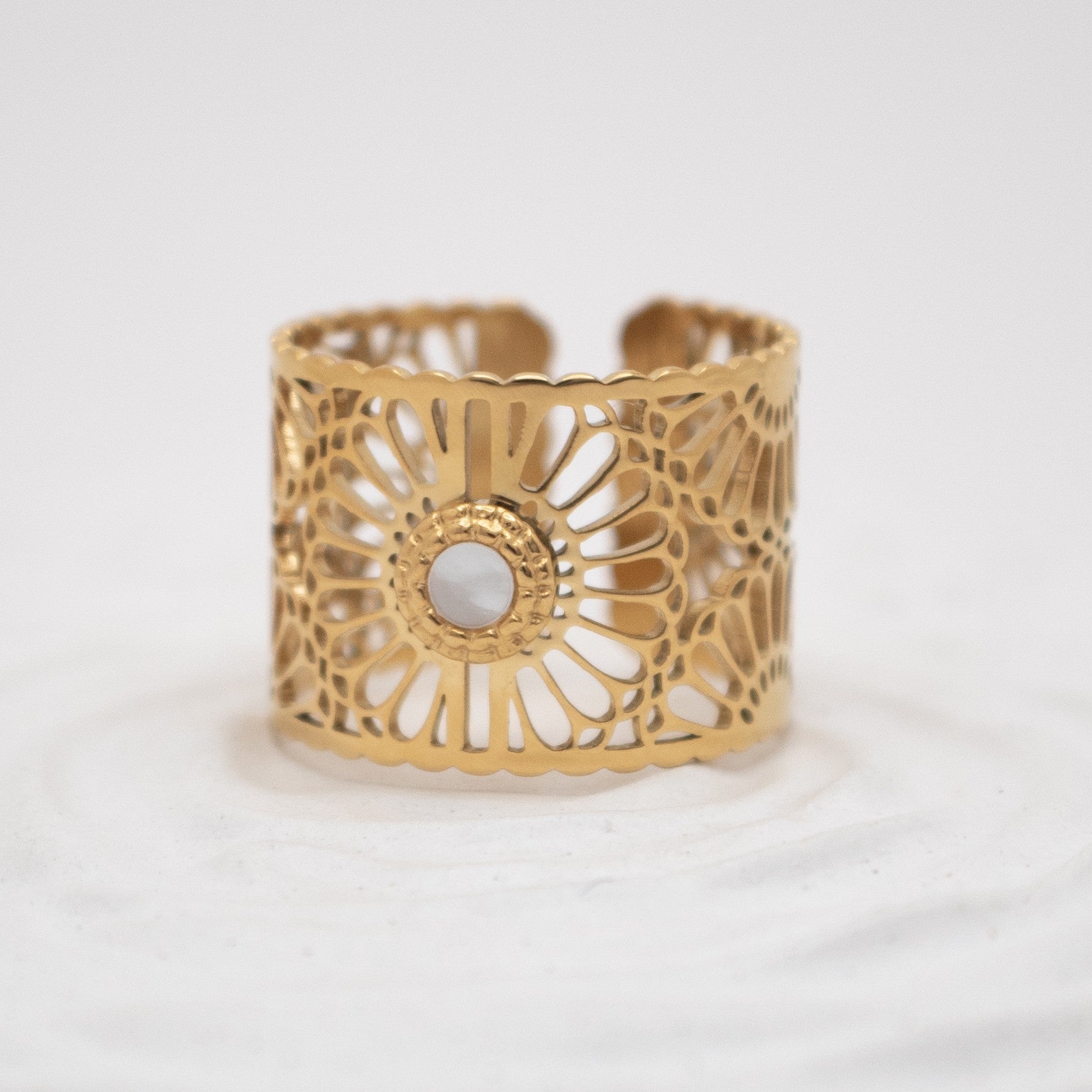 Gold cuff bracelet with intricate design on a white background