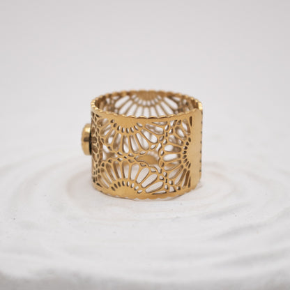 Gold bracelet with intricate design on a white background