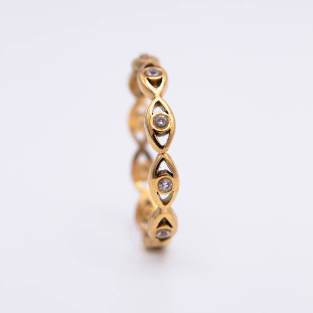 A gold eternity-style ring featuring a continuous row of small oval-cut stones, photographed on a clean white background.