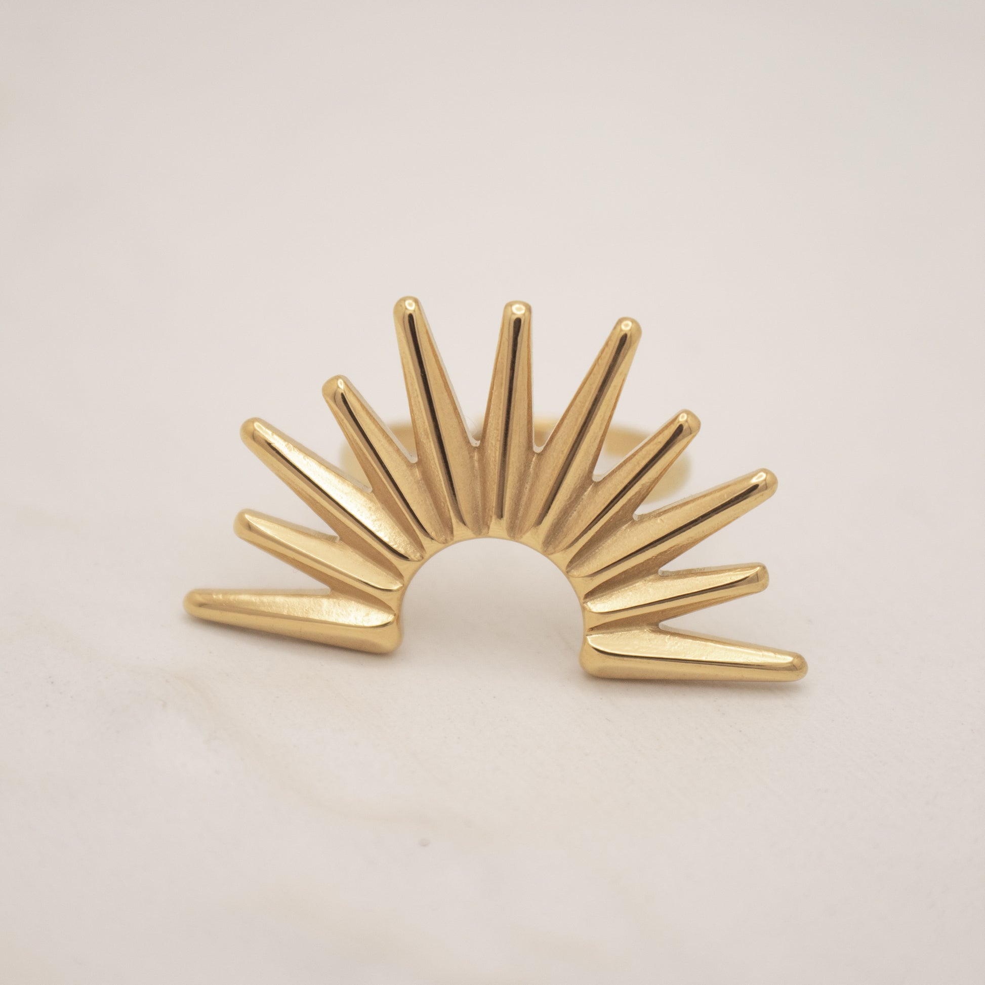 Gold sunburst ring on a beige background