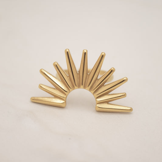 Gold sunburst ring on a beige background