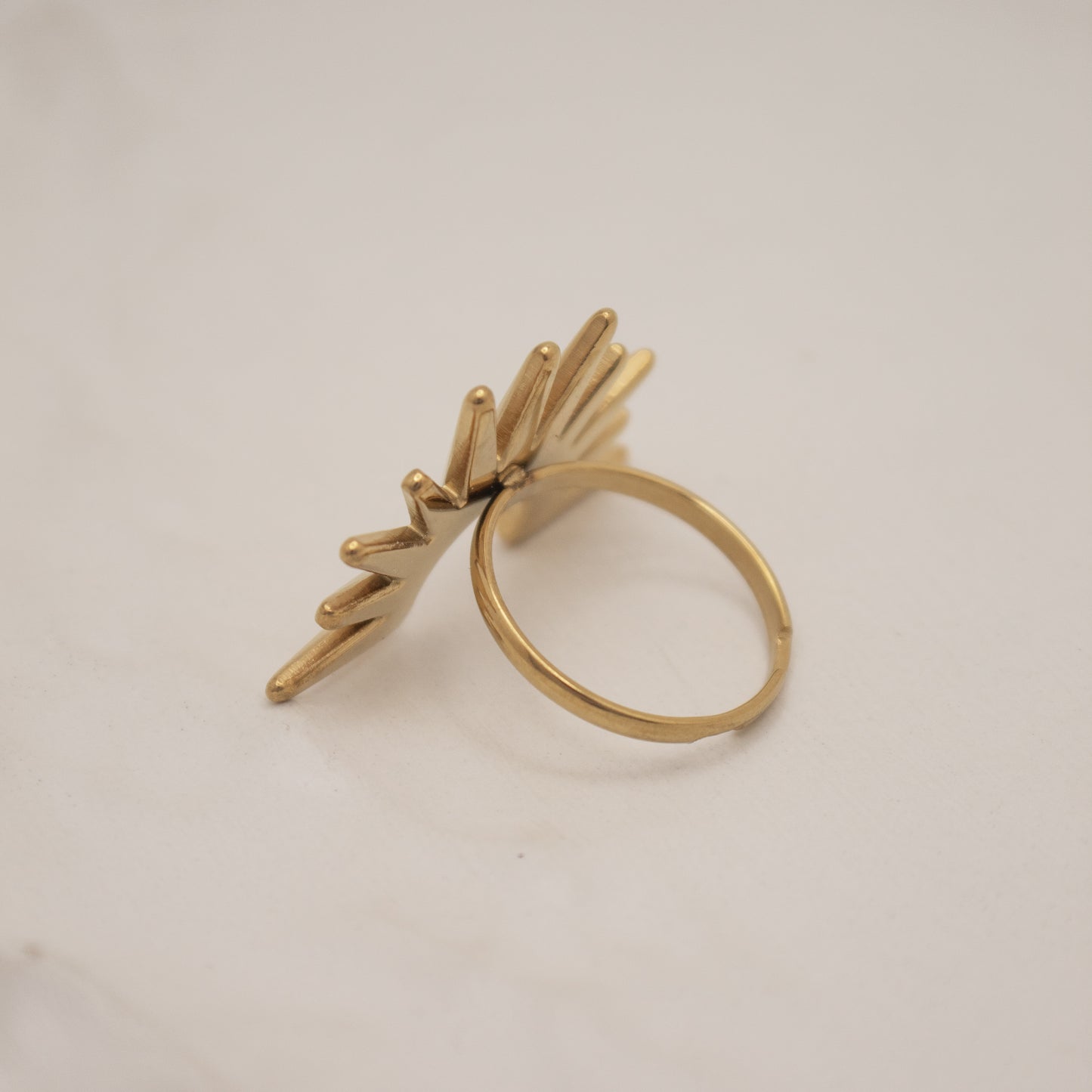 Gold ring with leaf-like design on a light gray background