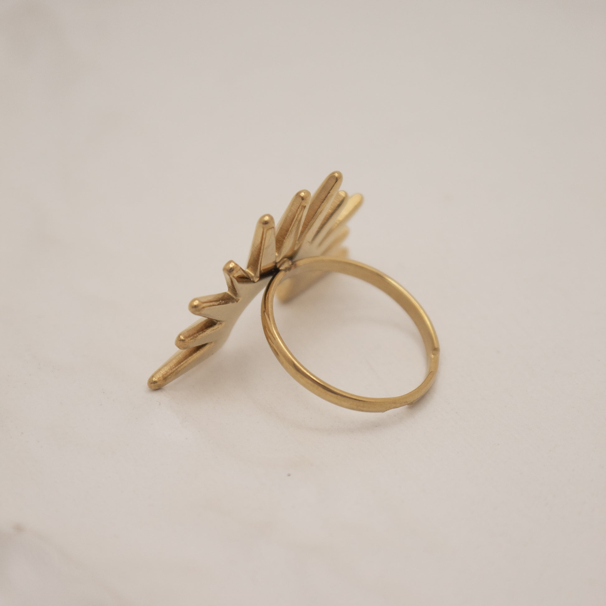 Gold ring with leaf-like design on a light gray background
