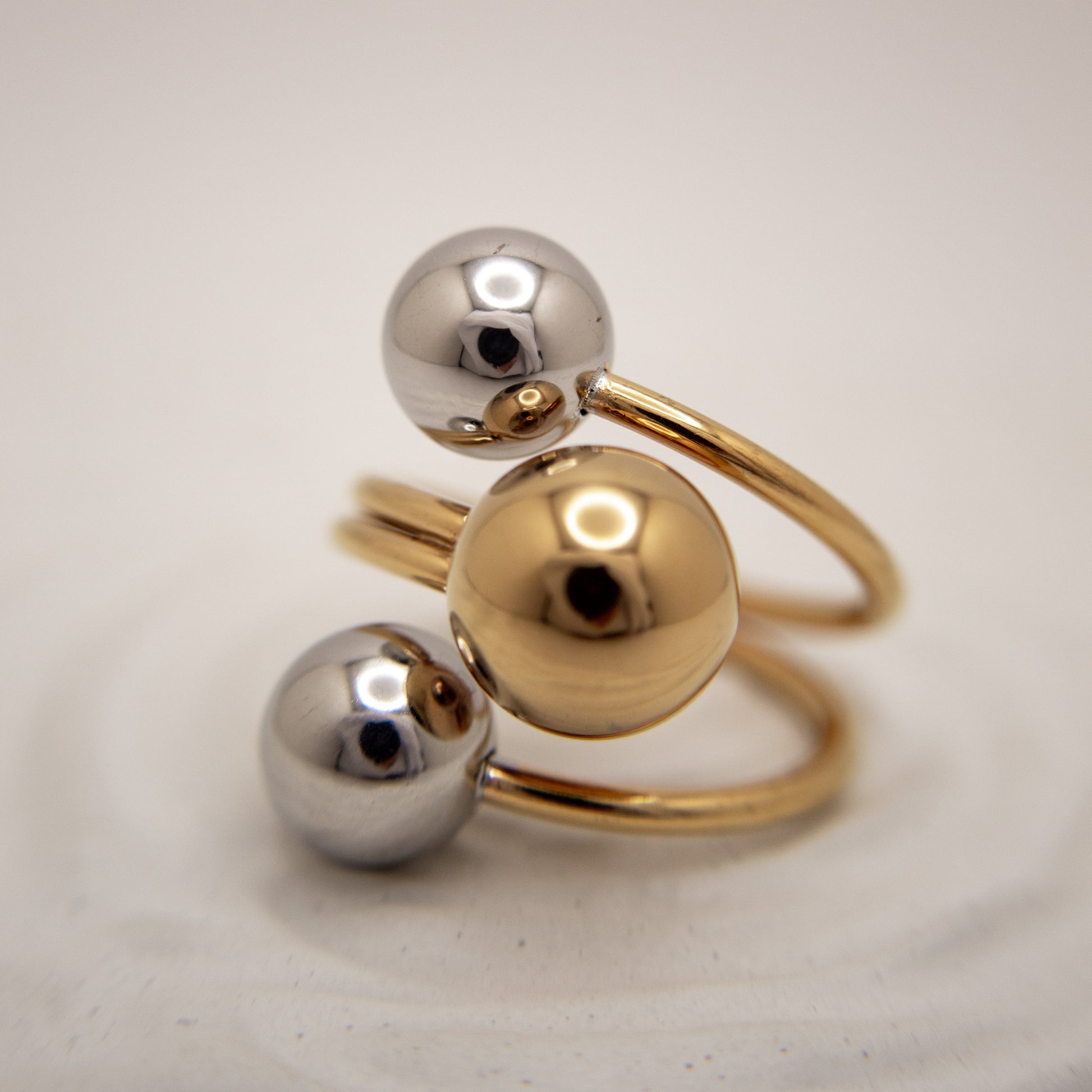 Gold and silver spherical ring on a light background