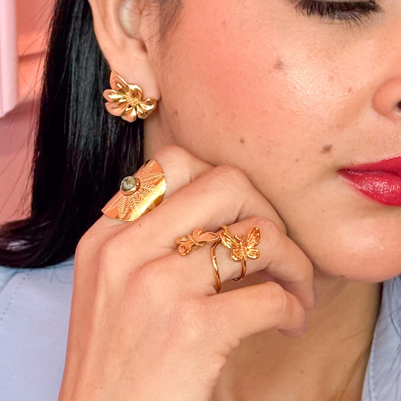 Close-up of a woman wearing gold floral earrings and a ring.