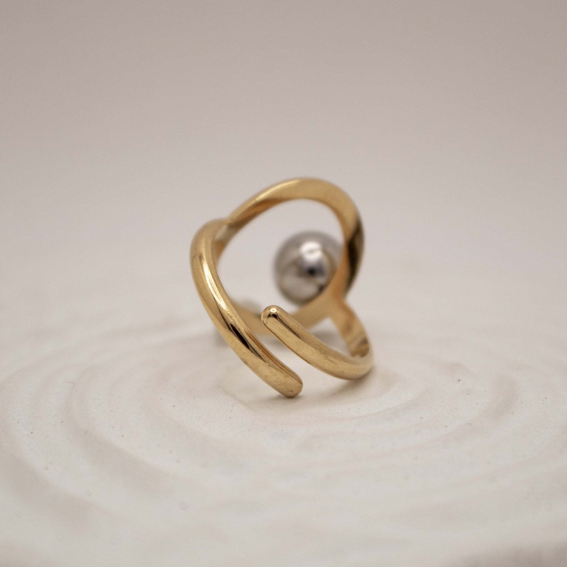 Gold ring with a pearl on a beige background