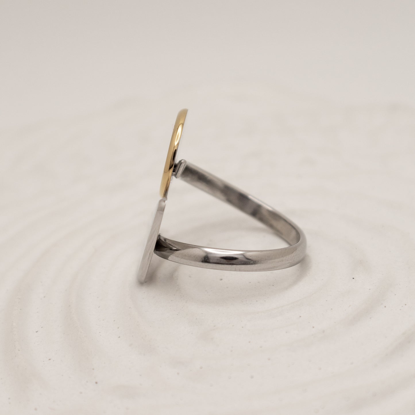 Silver ring with a gold accent on a light beige background