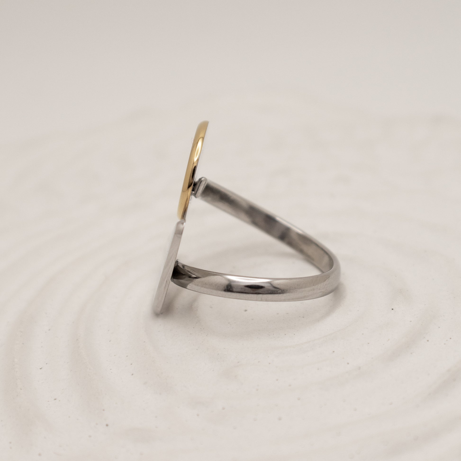 Silver ring with a gold accent on a light beige background