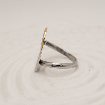 Silver ring with a gold accent on a light beige background