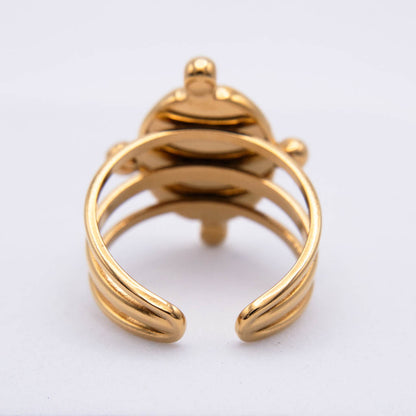 A gold-colored adjustable ring with a decorative top featuring a small central bead and side accents, shown on a plain white background.