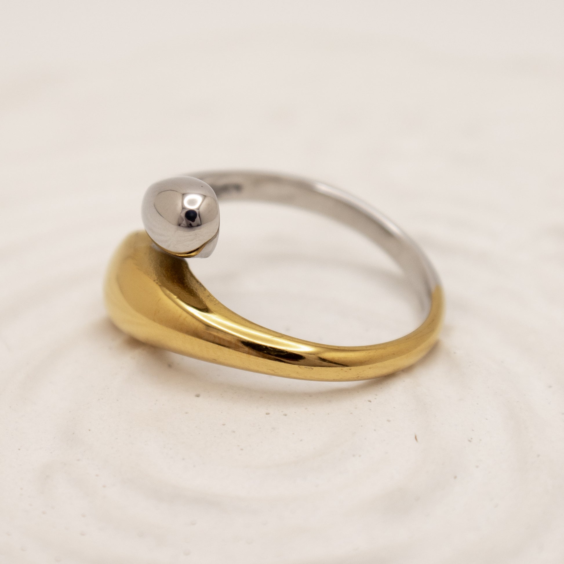 Two-tone gold and silver ring on a light beige background