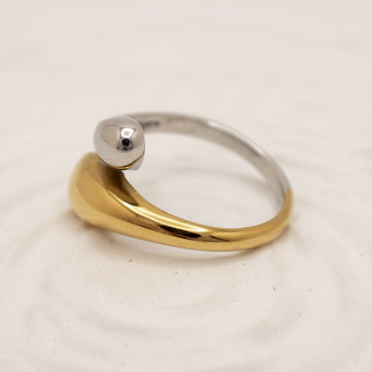 Two-tone gold and silver ring on a light beige background