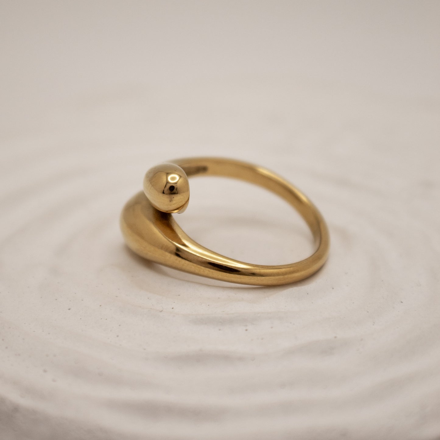 Gold ring with a spherical top on a beige fabric background