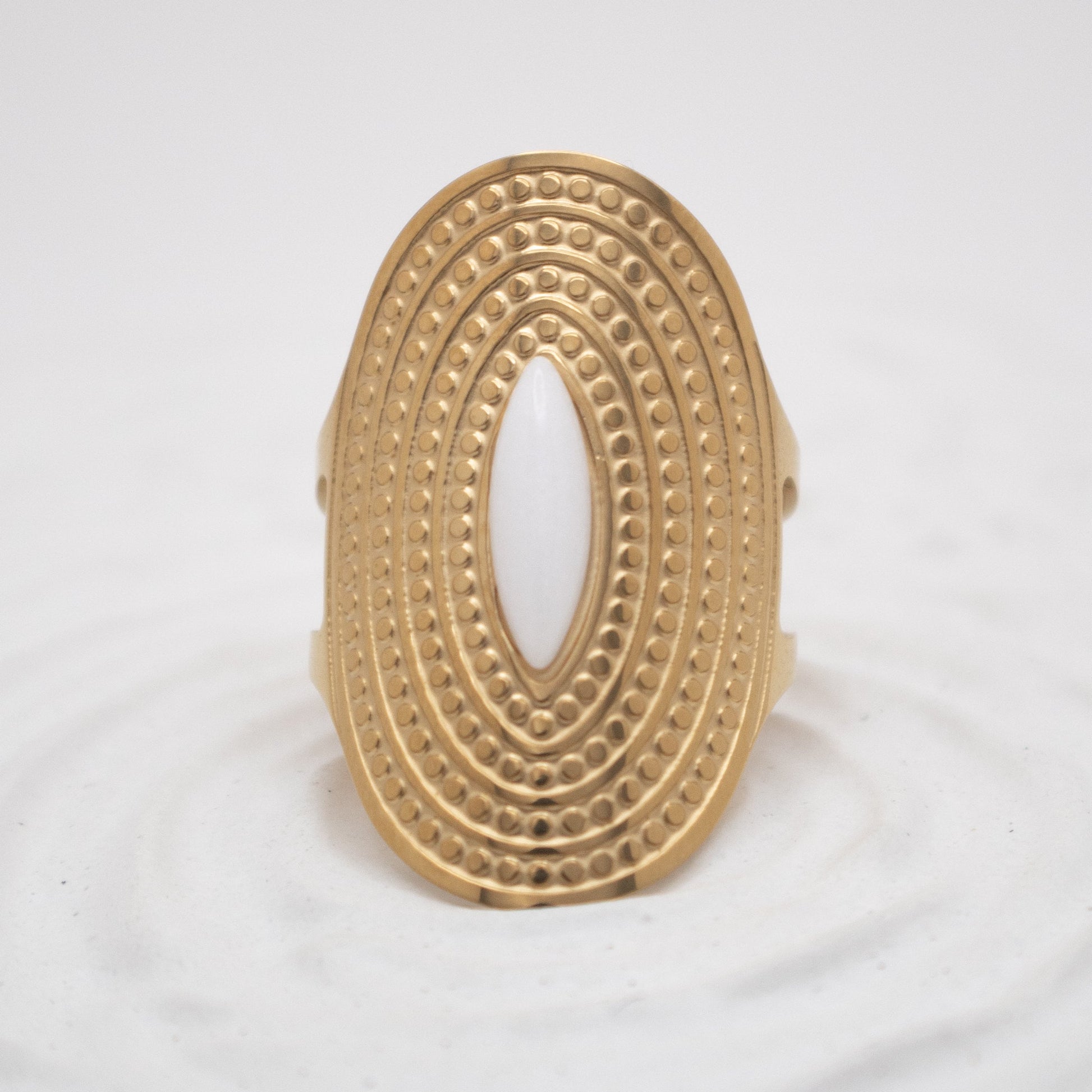 Gold ring with intricate design on a white background