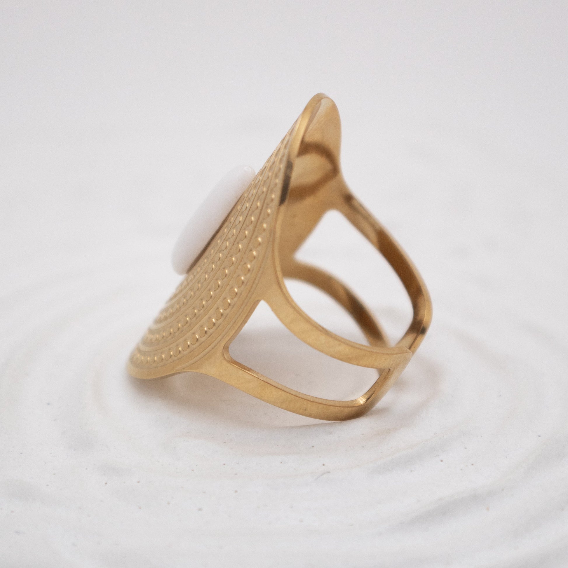Gold ring with a textured design on a white background