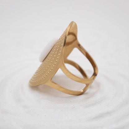 Gold ring with a textured design on a white background