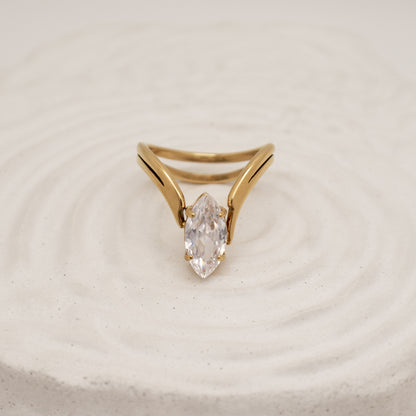 Gold ring with a clear gemstone on a beige background
