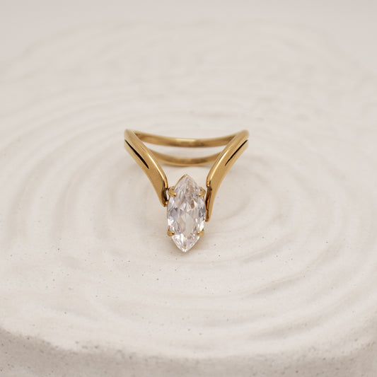 Gold ring with a clear gemstone on a beige background