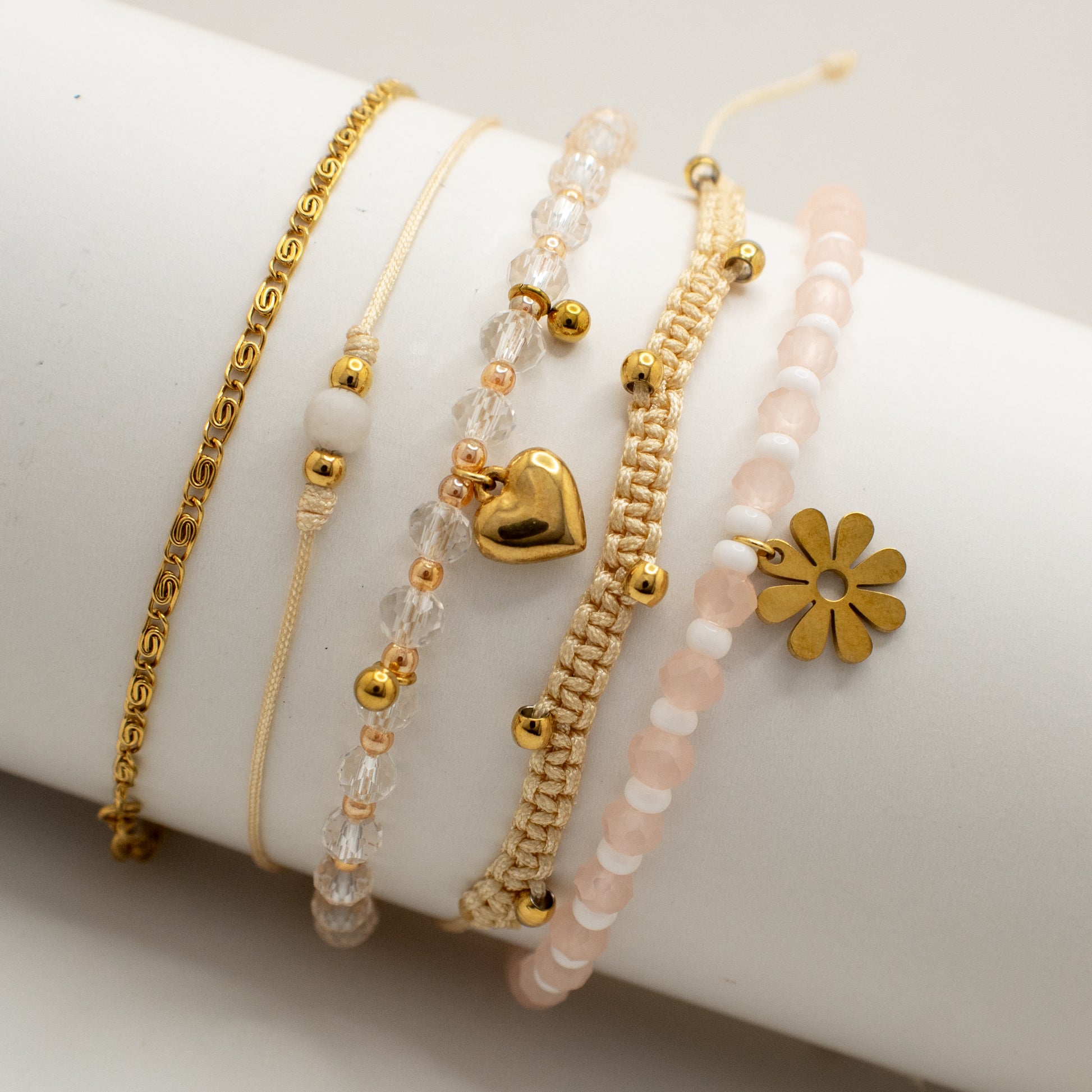 Set of gold and beaded bracelets on a white surface