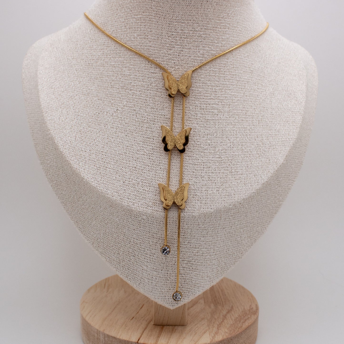 Butterfly-themed necklace on a mannequin bust with a white background