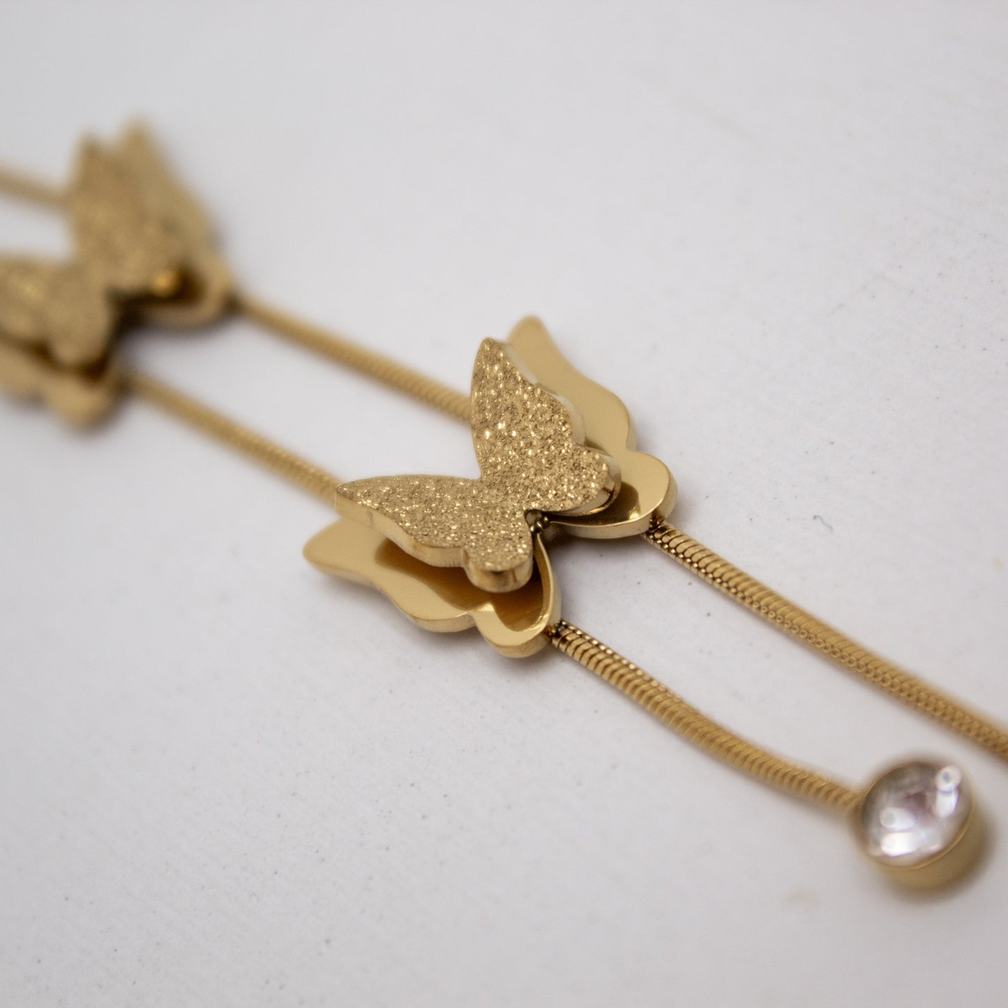 Gold butterfly necklace on a light gray background