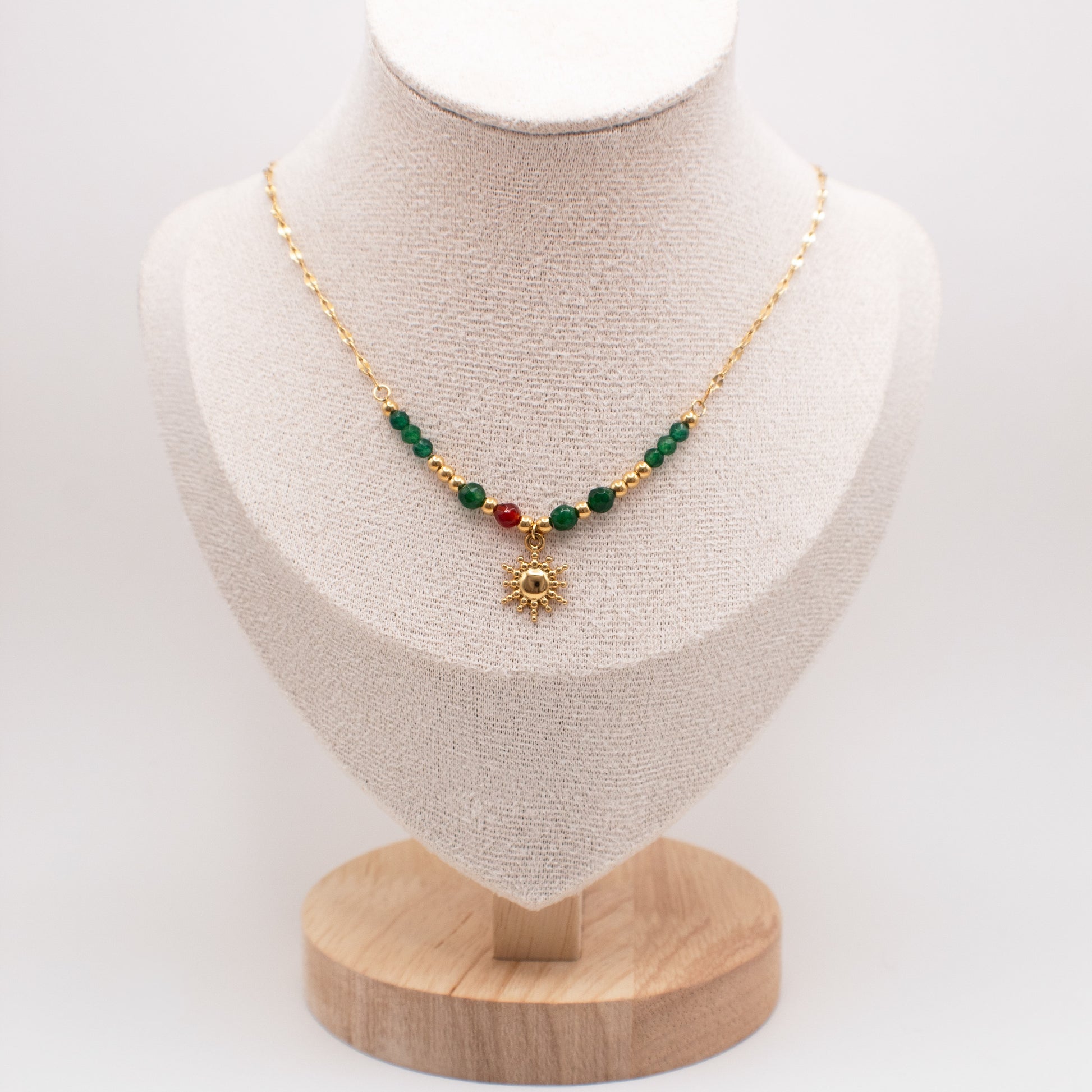 Necklace with green and red beads on a mannequin bust with a white background