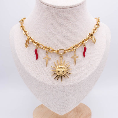 A gold-tone chunky chain necklace displayed on a cream fabric mannequin bust. The necklace features a central sun face charm, two lightning bolt charms, a small crescent moon charm, and two small red italian horns charms.