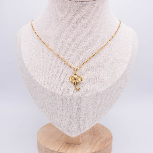A gold chain necklace with a small elephant pendant displayed on a textured cream fabric jewelry bust stand.