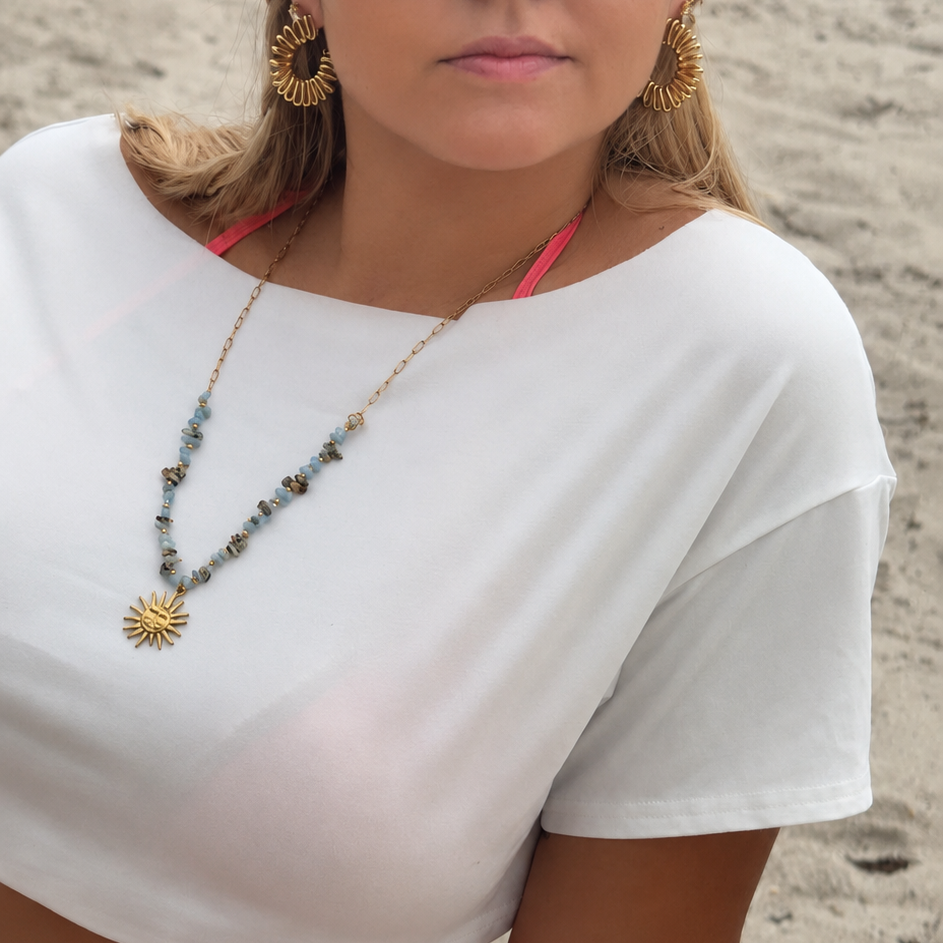 Woman wearing a white top and sunglasses on a beach