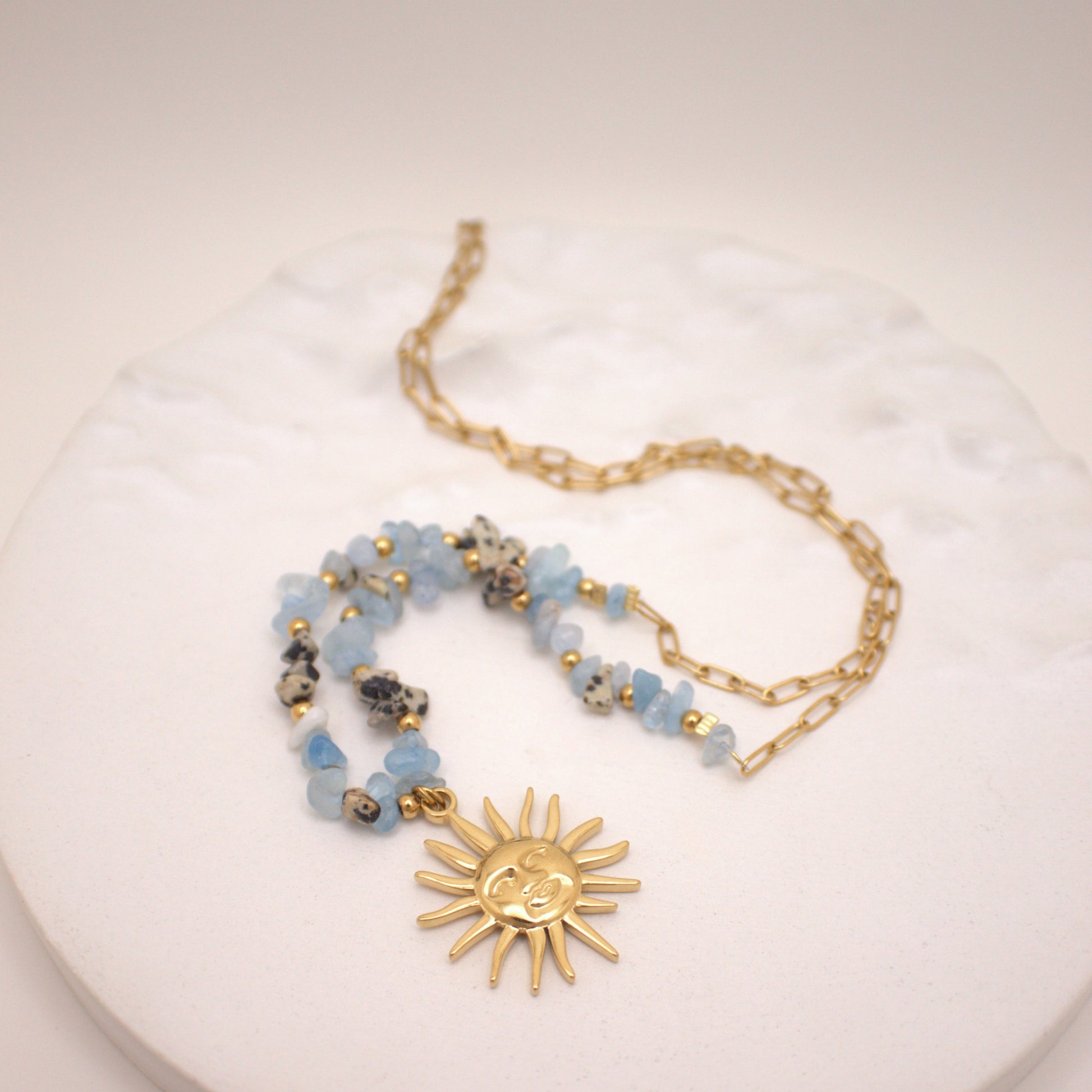 Necklace with sun pendant and beaded chain on a white surface