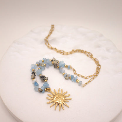 Necklace with sun pendant and beaded chain on a white surface